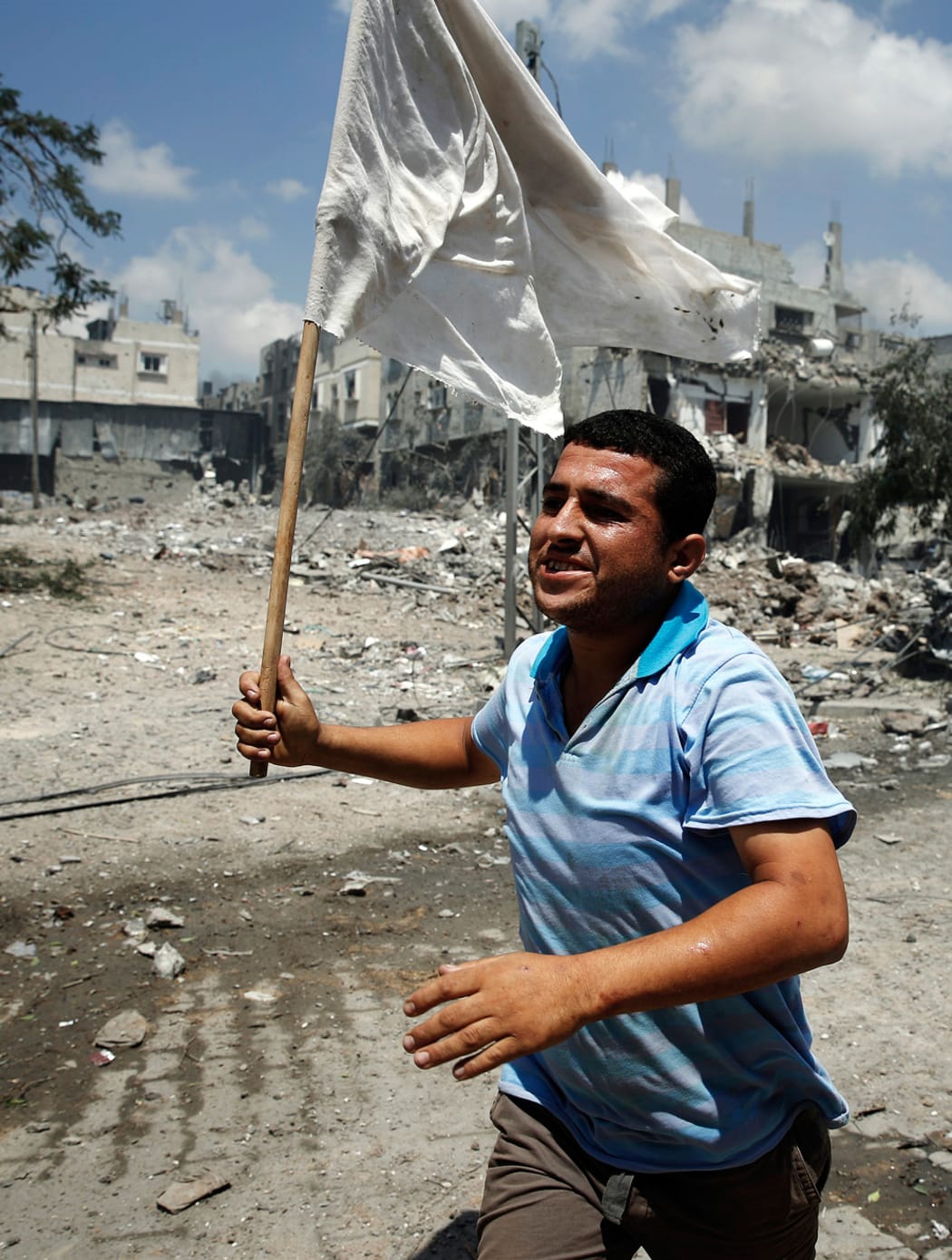 A Palestinian man runs with a white flag in the Shejaia neighbourhood of Gaza City.