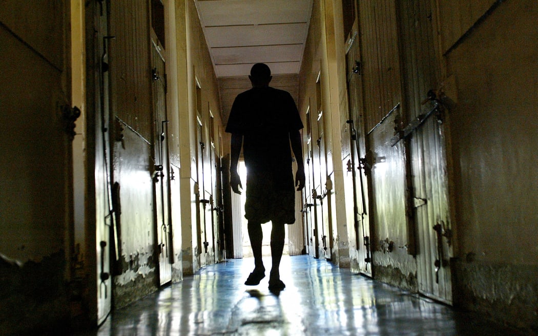 An asylum patient wanders through the hall containing the men's cells at the decrepit St Giles Psychiatric Hospital hidden in the jungle-clad hills overlooking Suva, 24 February 2004.  Due to a severe funding crisis there are only four doctors left to care for over 150 patients in facilities which date back to 1884. Suicide from depression, schizophrenia and mania now surpass road deaths and drownings in Fiji due to the lack of employment opportunities, the state of the economy, and the uncertainty over land leases.  AFP PHOTO/Torsten BLACKWOOD (Photo by TORSTEN BLACKWOOD / AFP)