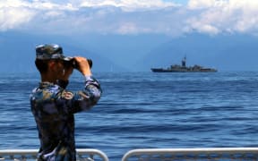A soldier looks through binoculars during combat exercises and training of the navy of the Eastern Theater Command of the Chinese People's Liberation Army (PLA) in the waters around the Taiwan Island, 5 August, 2022. T