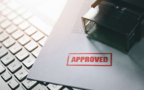 document with approved stamp on computer keyboard