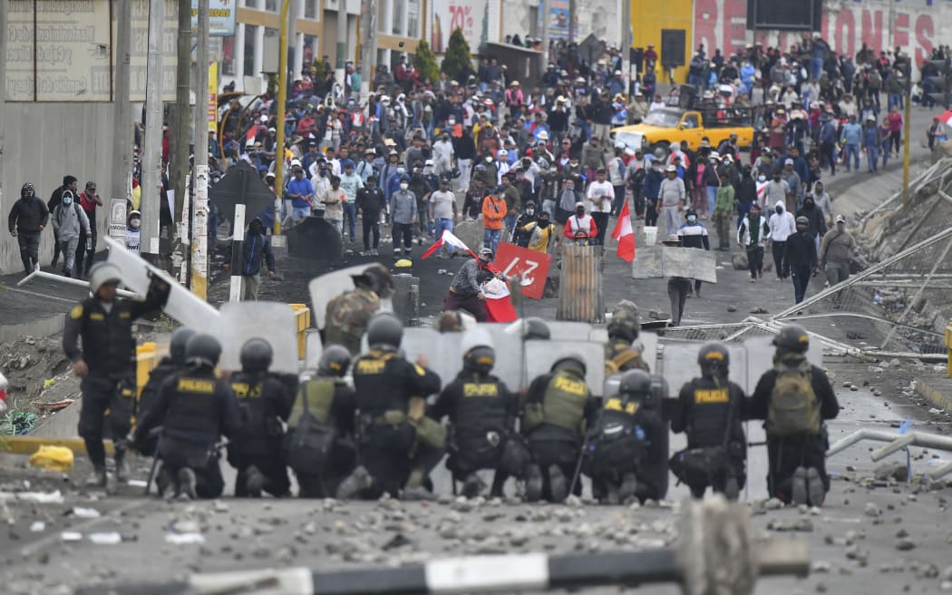 Demonstrators clash with riot police at the Añashuayco bridge in Arequipa, Peru, during a protest against the government of President Dina Boluarte and to demand her resignation on January 19, 2023. - After weeks of unrest, thousands of protesters were expected to descend on Peru's capital Lima, defying a state of emergency to express their anger with President Dina Boluarte, who called on the demonstrators to gather "peacefully and calmly". The South American country has been rocked by over five weeks of deadly protests since the ouster and arrest of her predecessor Pedro Castillo in early December. (Photo by Diego Ramos / AFP)