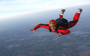 a man sky diving in a red suit and helmet