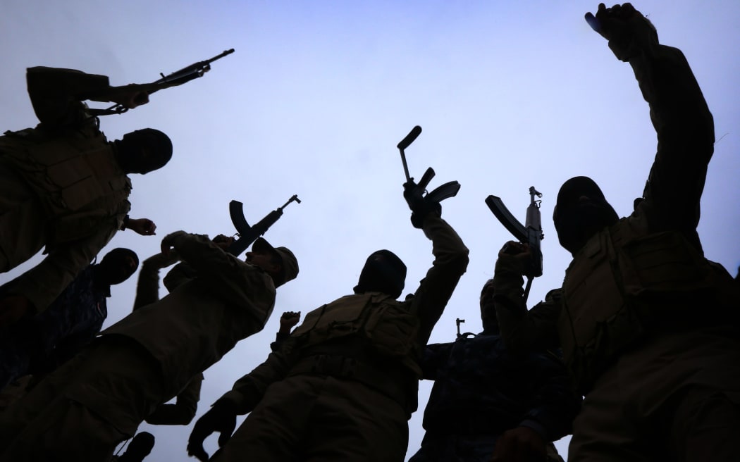 Iraqi policemen raise their weapons during a training session as they prepare to recapture Mosul from Islamic State fighters.