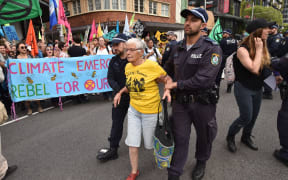 An Extinction Rebellion activist (C) is arrested by police after hundreds of protesters staged a sit-in on a busy inner-city road in Sydney on October 7, 2019.