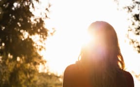 Rear view of silhouetted mid adult woman gazing over mountain forest at sunset, Palomar, California, USA (Photo by Yew! Images / Connect Images / Connect Images via AFP)