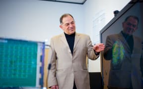 Nikola Kasbov standing in front of a monitor showing a graphical representation of a neural network