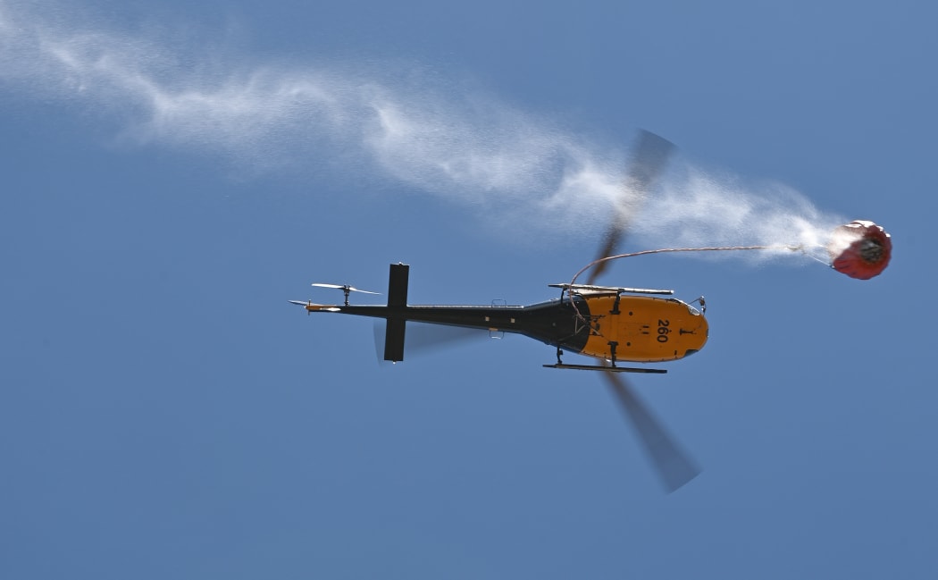 A helicoptor drops water on an out of control bushfire near Taree, 350km north of Sydney on November 12, 2019