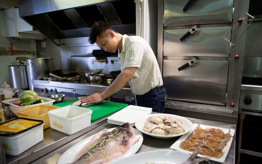 Chef Kenny Zhu, co-owner of Zhu Kitchen on Dominion Road, prepares to cook a fish brought in by a customer.