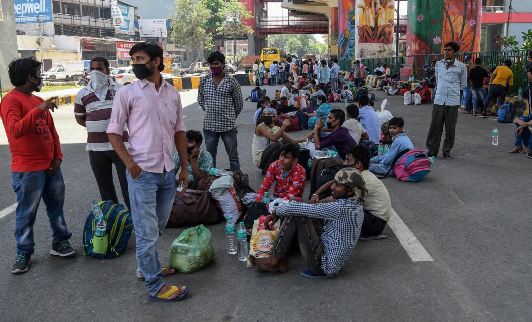 Migrant workers and families wait for transport to go back to their native places after the goverment eased a nationwide lockdown imposed as a preventive measure against the COVID-19 coronavirus, in Ghaziabad on May 16, 2020.