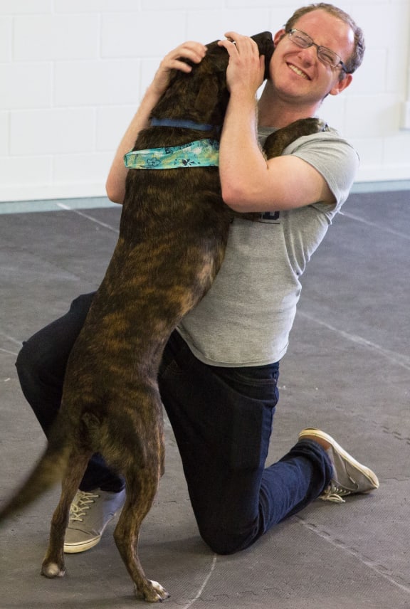 A dog enjoys visiting the Clever Canine Lab and meeting student Patrick Neilands.