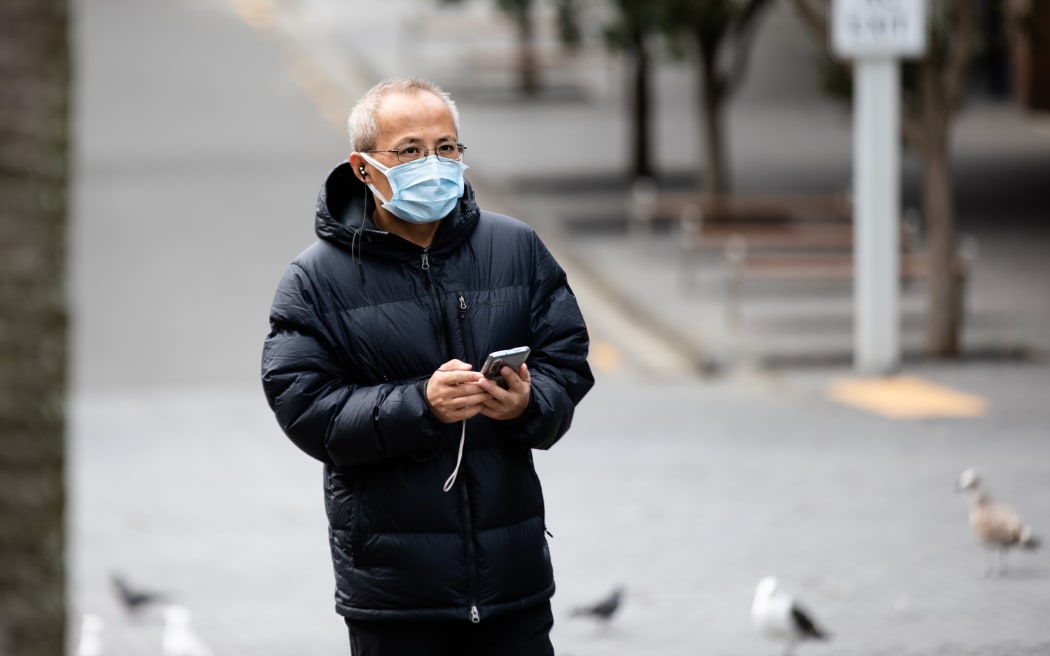 A man wearing a mask collects takeaways near Auckland's Queen Street.