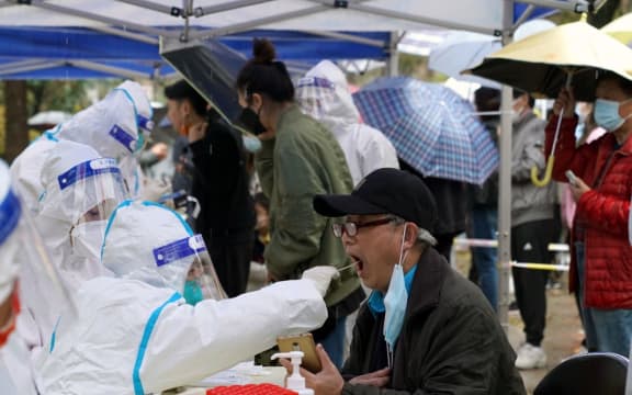 Citizens receive nucleic acid tests at a residential area in east China's Shanghai, March 17, 2022.