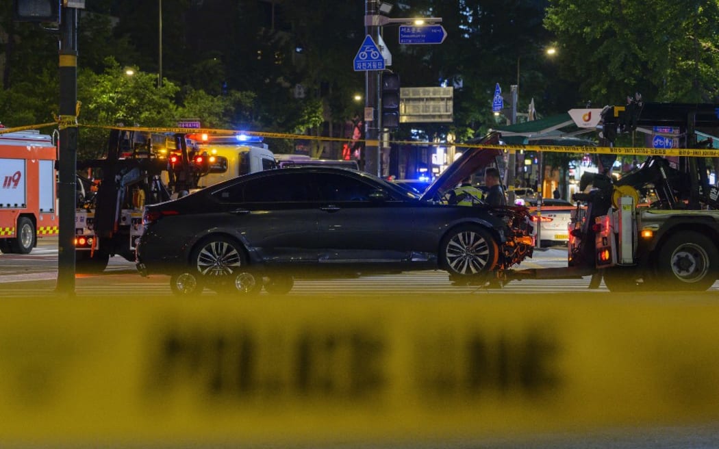 Emergency workers and vehicles are seen near a car that was involved in an accident, which left at least nine people dead, in Seoul late on July 1, 2024. At least nine people were killed and four others were injured when a car struck pedestrians near Seoul city hall on July 1, police said. (Photo by ANTHONY WALLACE / AFP)