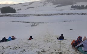 Children playing in the snow on a farm in Owaka, South Otago.