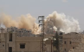 Smoke rises amid damaged buildings as the Assad regime forces carry out barrel bomb attack the opposition-controlled areas in the Darayya district in the southwest Damascus, Syria on June 10, 2016.
