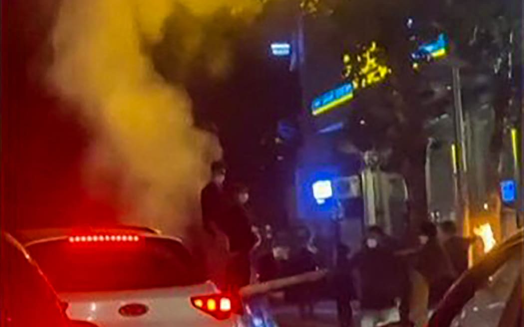 This grab taken from a UGC video made available on the ESN platform on 15 November, 2022, shows Iranian protesters blocking traffic in the northern city of Rasht as they chant "freedom" while removing a street sign.