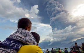 Residents watch the eruption of Mount Lewotobi Laki Laki from Eputobi village in Titihena, East Nusa Tenggara, on November 8, 2024. (Photo by Bayu ISMOYO and ARNOLD WELIANTO / AFP)