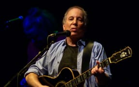 Musician Paul Simon performing with guitar