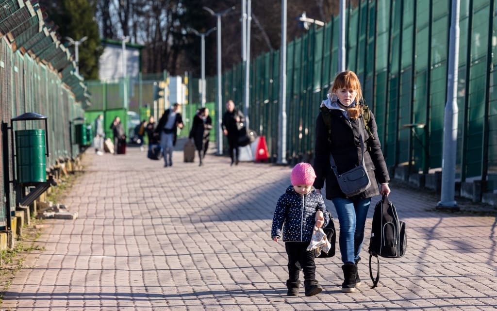 Ukrainian families walk through the Medyka border crossing into Poland after Russia bombarded Ukraine.