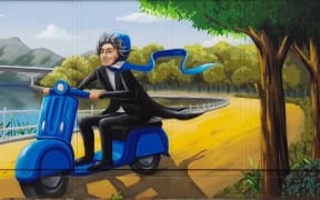 A caricature of Beethoven driving a blue motor scooter (and wearing a matching helmet) along a path next to a river.