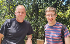 Ecologists with an interest in epiphytes: KC Burns and Tom Dawes stand in front of a climbing rata growing up a larger tree.