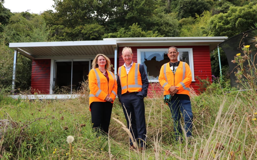 Nelson City Council recovery taskforce members from left, councillor Trudie Brand, Mayor Nick Smith and councillor Matty Anderson in front of one a red-stickered Rocks Road house that has been bought by council and will be demolished.