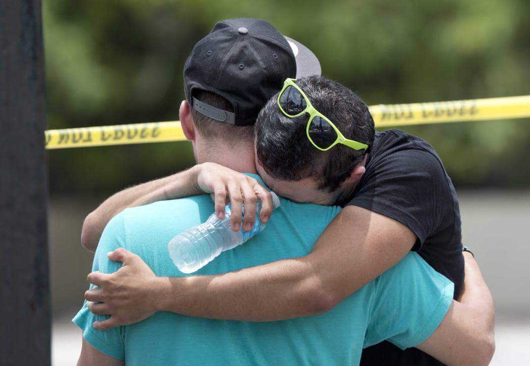 Supported by a friend, a man weeps for victims of the mass shooting just a block from the scene in Orlando, Florida, on June 12, 2016.