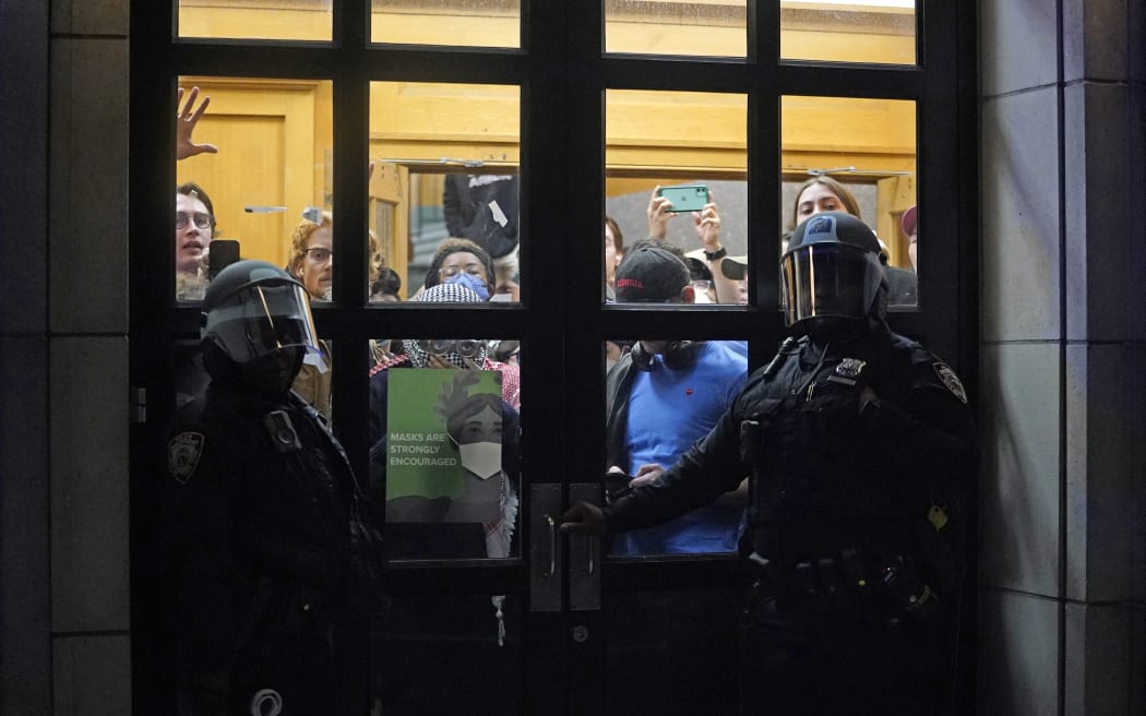 NYPD officers stand next to barricaded students at Columbia University in New York City on April 30, 2024.