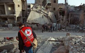 A International Red Cross volunteer stands above the rubble of a destroyed building in Douma, Eastern Ghouta, Syria on March 5, 2018.