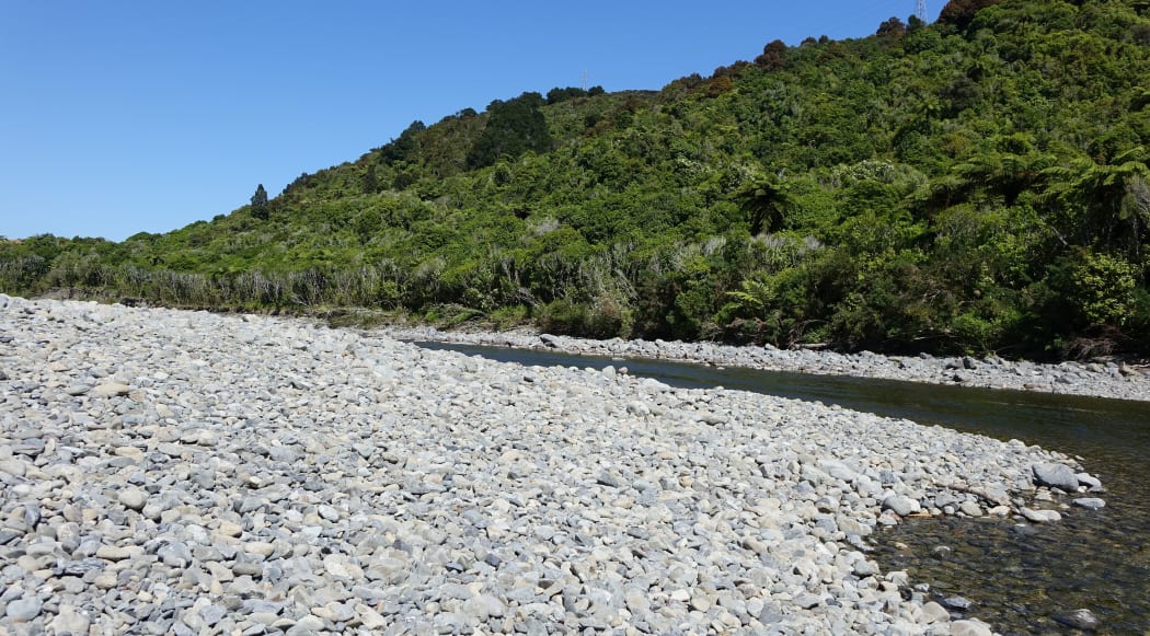 Wide stone bank with curving river and bush clad bank on far side