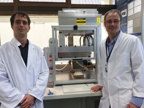 A photo of Ben Schon and Tim Woodfield in front of the 3D bioprinter