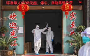 Medical staff member (left) being disinfected by a colleague before leaving a quarantine zone converted from a hotel in Wuhan, 3 February 2020.