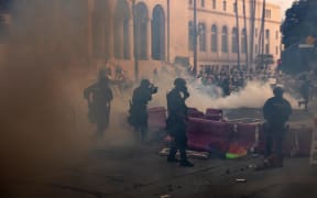Los Angeles police officers advance on a makeshift barricade in a cloud of tear gas as clashes erupt with demonstrators next to City Hall during a protest following federal immigration operations, in Los Angeles, California on June 8, 2025. Demonstrators torched cars and scuffled with security forces in Los Angeles on June 8, as police kept protestors away from the National Guard troops President Donald Trump sent to the streets of the second biggest US city. (Photo by ETIENNE LAURENT / AFP)