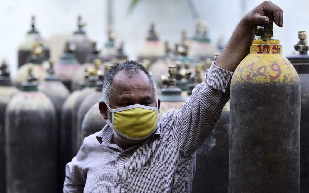 A man waits to refill a medical oxygen cylinders for a Covid-19 coronavirus patient at an oxigen refile station in Allahabad on April 20, 2021 (Photo by SANJAY KANOJIA / AFP)