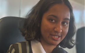 Head and shoulders shot of Emma Dias holding a microphone.