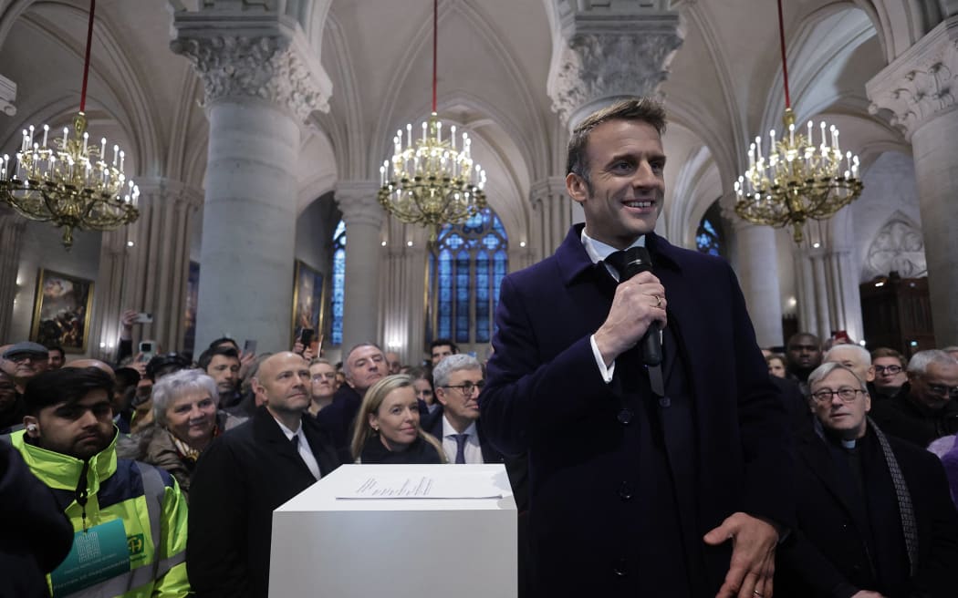 Attendees including workers of reconstruction of Notre-Dame de Paris cathedral gather during a speech by French President Emmanuel Macron (C) in the nave of the cathedral in Paris, on November 29, 2024. - The Notre-Dame Cathedral is set to re-open early December 2024, with a planned weekend of ceremonies on December 7 and 8, 2024, five years after the 2019 fire which ravaged the world heritage landmark and toppled its spire. (Photo by Christophe PETIT TESSON / POOL / AFP)