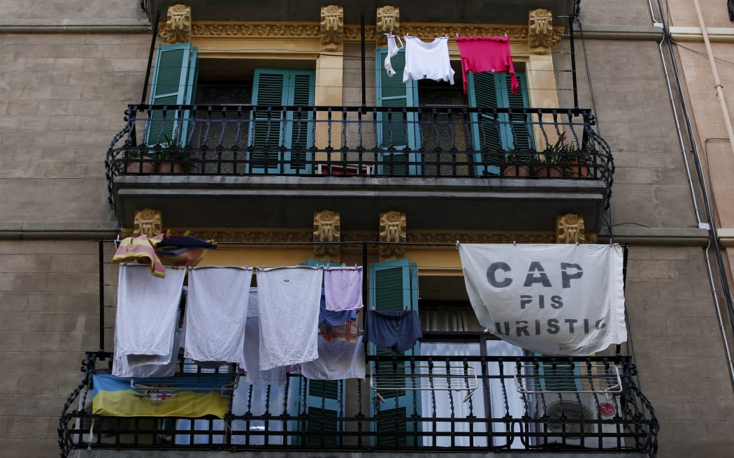 A banner reading "No tourist flats" hangs from a balcony to protest against holiday rental apartments for tourists in Barcelona's neighborhood of Barceloneta on November 24, 2016. Barcelona city hall said today it would fine home rental websites Airbnb and rival HomeAway 600,000 euros ($635,000) each for marketing lodgings that lacked permits to host tourists. (Photo by PAU BARRENA / AFP)