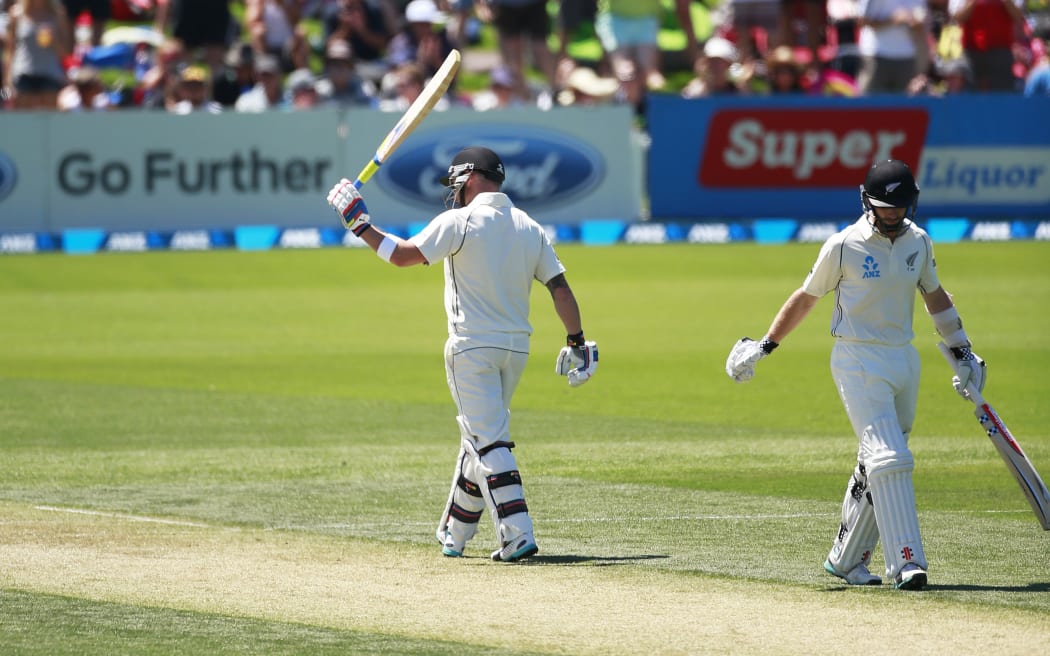 Brendon McCullum raises his bat after passing the 1,000-run milestone