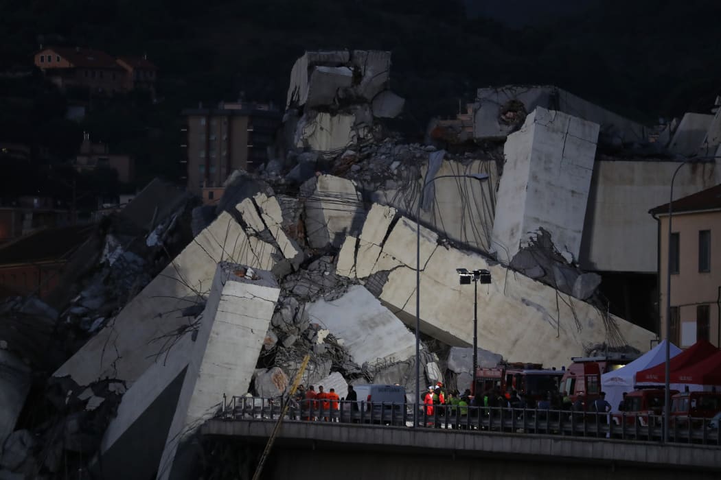 Rescuers inspect the rubble after a section of a motorway bridge collapsed earlier in Genoa.