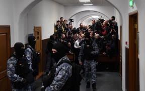 Russian law enforcement officers stand guard as journalists wait for suspects in the deadly attack on the Crocus City Hall to appear at the Basmanny District Court in Moscow on 24 March, 2024. Russia observed a national day of mourning on 24 March, 2024 after a massacre in a Moscow concert hall that killed 137 people, the deadliest attack in Europe to have been claimed by the Islamic State jihadist group.