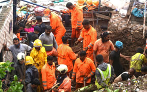Rescue team personnel inspect the site of the landslide in a slum area where 25 people were killed after several homes were crushed by a collapsed wall and a landslide triggered by heavy monsoon rains in Mumbai.