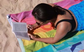 A woman reads a book on the beach. Illustration reading, summer, summer holidays and tourism.