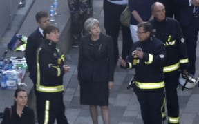 British Prime Minister Theresa May meeets firefighters as she visits the remains of Grenfell Tower.