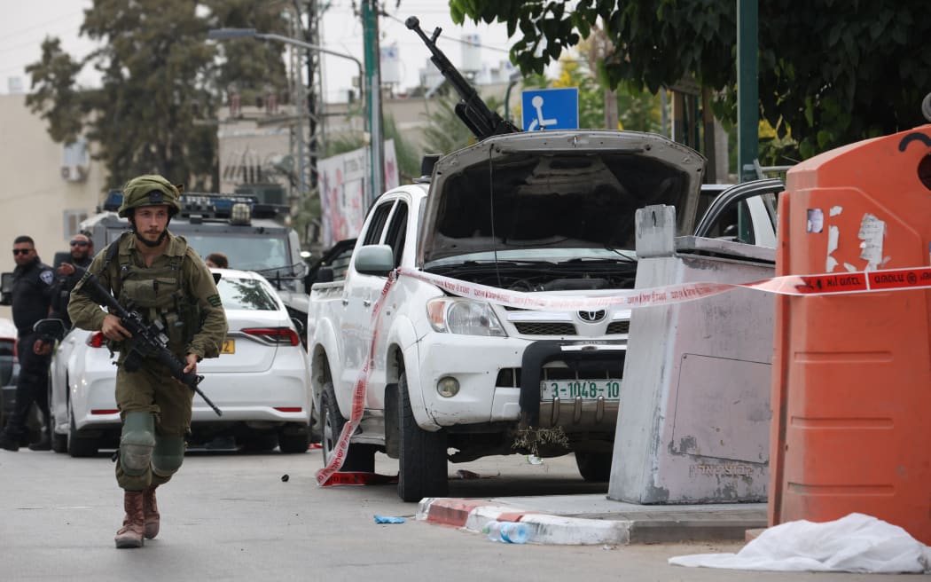 An Israeli soldier stands guard next to a pickup truck mounted with machine gun in the southern city of Sderot on 7 October, 2023, after the Palestinian militant group Hamas launched a large-scale surprise attack on Israel.