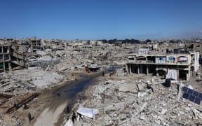 Palestinians make their way through the rublle of destroyed buildings in the Sheikh Radwan neighbourhood of Gaza City on February 4, 2026. Despite a US-brokered truce entering its second phase earlier in January, violence in the Palestinian territory has continued, with both Israel and Hamas accusing each other of violating the agreement. (Photo by Omar AL-QATTAA / AFP)