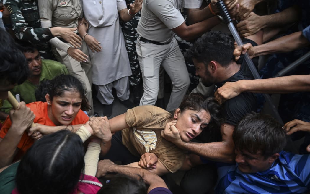 Indian wrestlers Sangeeta Phogat, left, and Vinesh Phogat, centre, are detained by the police while attempting to march to India's new parliament during a protest against Brij Bhushan Singh, the wrestling federation chief, over allegations of sexual harassment and intimidation, in New Delhi on 28  May, 2023.