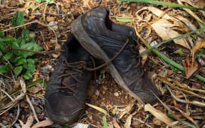89175150 - pair of dirty old black shoes abandoned outdoors in landscape format