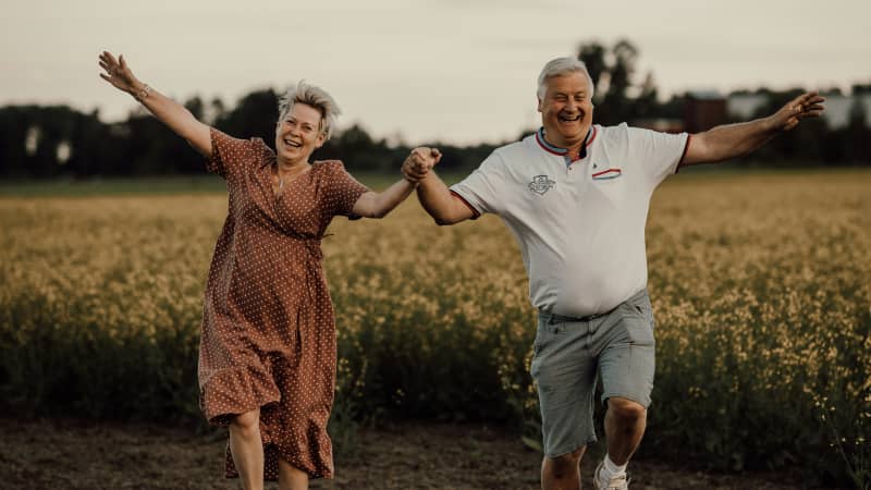 An older couple holding hands and skipping joyfully.
