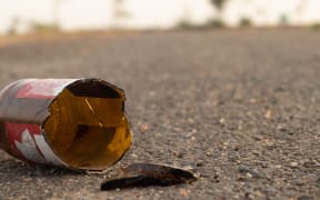 A brown glass bottle of beer broken on the road.