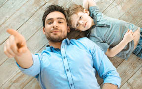 A photo of a father and son lying on the ground